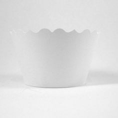 a white paper bowl with scalloped edges sits on a plain surface, ready to be used as an appetizer