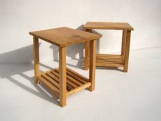 two small wooden tables sitting next to each other on a white surface with shadow from the wall behind them