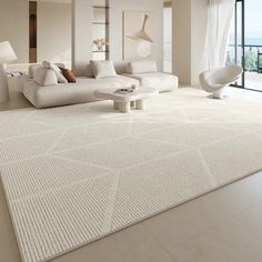 a large living room with white furniture and floor to ceiling windows looking out onto the ocean