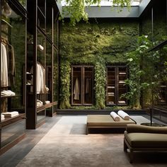 an open closet with green plants on the wall and clothes hanging in glass doors, along with two chaise lounges