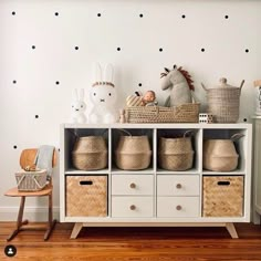 a white shelf with baskets and stuffed animals on it next to a polka dot wall