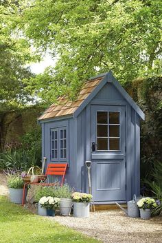 a small blue shed sitting in the middle of a garden