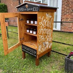 a beehive made out of wood and painted with honey on the side, sitting in front of a brick building