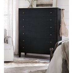 a black chest of drawers in a room with white walls and rugs on the floor