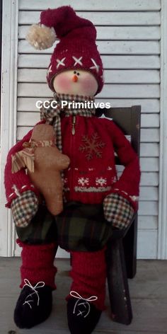 a teddy bear wearing a red sweater and plaid pants sitting on a chair with a stuffed animal in it's lap