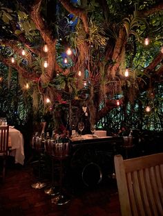 an outdoor dining area is lit up with fairy lights and greenery on the trees