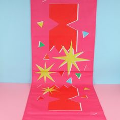 an art project made out of pink paper with stars and shapes on the bottom half