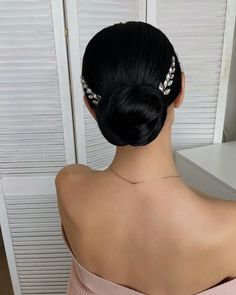 a woman with black hair wearing a pink top and some white flowers in her hair