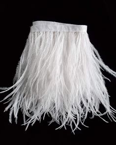 a lamp shade with white feathers hanging from it's side on a black background