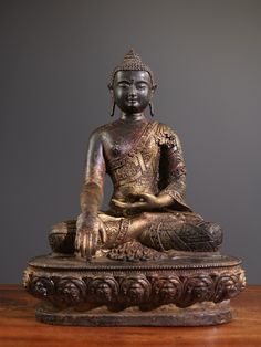 a buddha statue sitting on top of a wooden table