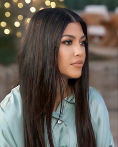 a woman with long dark hair wearing a blue shirt and looking off to the side