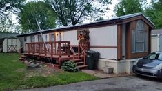 a mobile home is shown with a car parked in front of it and another house behind it