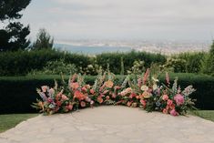 an outdoor ceremony with flowers and greenery on the ground in front of a view