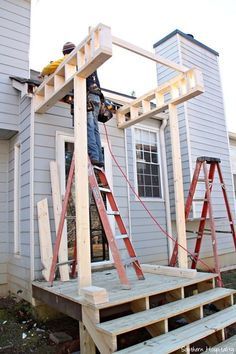 a man standing on top of a step ladder next to a house with windows and siding