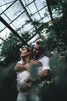 a man and woman embracing in a greenhouse