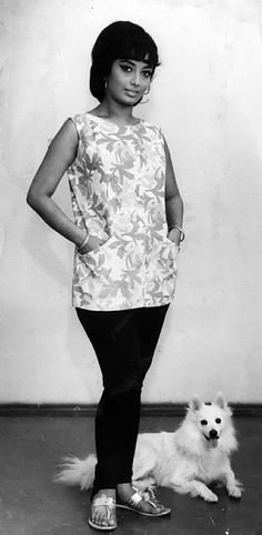 a black and white photo of a woman standing next to a dog on the floor