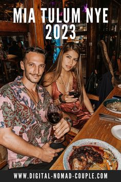 two people sitting at a table with food and wine