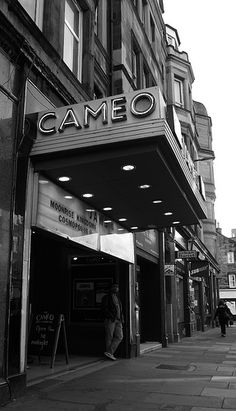 a black and white photo of people walking in front of a theater called cameo