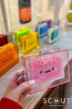 a person holding up a pink cassette tape recorder in front of some colorful plastic boxes