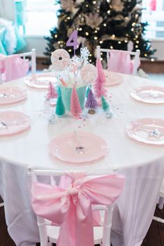 the table is set with pink and white plates, napkins, and candy trees