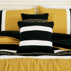 a bed with black and yellow pillows on it