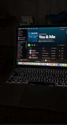 an open laptop computer sitting on top of a black table with the screen lit up