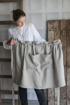 a woman is holding up a piece of linen in front of her face and looking down at the fabric