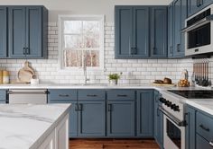 a kitchen with blue cabinets and marble counter tops