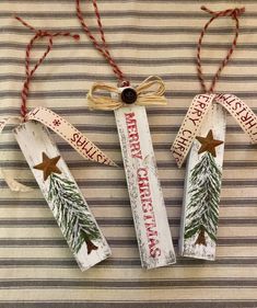 three wooden christmas decorations on a striped tablecloth