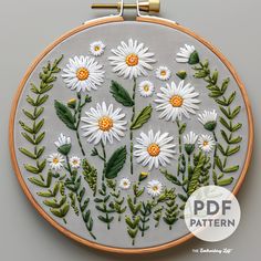 the embroidery pattern has daisies and leaves on it