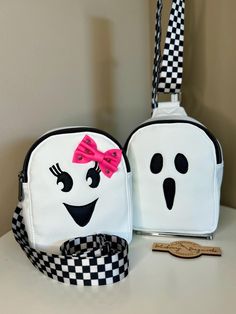 It's always spooky season with this adorable Ghost Sling! This cute little sling is the perfect grab n' go size.  Carry all of the essentials within easy reach; this sling just right for a phone, wallet, keys, sunglasses and maybe a snack or two :) A white faux leather body looks great with the hand appliquéd ghost details. The adjustable black and white checkered strap can be clipped on either side of the bag for either right or left handed wear.  A waterproof interior and a small interior zipp Fun White Backpack Bag, Fun White Backpack, Cute Bags For Everyday Use And Halloween, Halloween White Backpack, White Backpack For Halloween, White Halloween Backpack, Boo Boo Bags, Small Sling Bag, Coin Purse Wallet