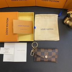 the louis vuitton wallet and keychain are on display in an orange box