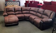 a large sectional couch with multiple recliners in a room filled with red chairs