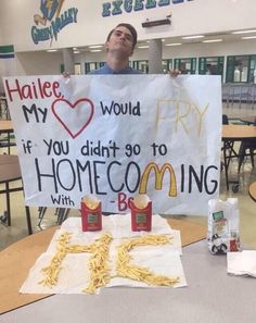 a man holding up a sign at a table with some food and drinks on it