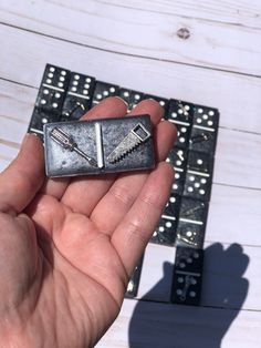 a hand holding a small metal object in front of some dominos on a table