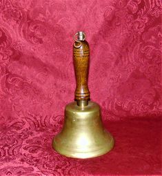 a brass bell with a wooden handle on a red background