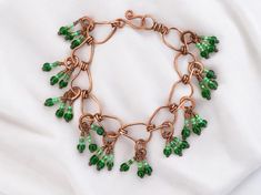 This lightweight copper beaded charm bracelet features 100% handmade copper links hung with multicolored green glass beaded charms This organic deco jewelry lends a sophisticated tropical accent to compliment your style and elevate any outfit. This bracelet is part of the Mangrove collection, inspired by the mangrove marshes of South Florida, with copper elements evoking the branching exposed roots and deep green accents evoking lush plant life that is beautifully cohesive and unique in the worl Copper Jewelry With Dangling Beads, Bohemian Green Copper Jewelry, Green Metal Beaded Bracelets For Jewelry Making, Green Wire Wrapped Czech Glass Jewelry, Green Bohemian Metal Beaded Bracelets, Green Bohemian Metal Beaded Bracelet, Green Copper Jewelry For Jewelry Making, Wire Wrapped Copper Green Jewelry, Green Wire Wrapped Copper Jewelry