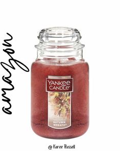 a jar filled with red colored liquid next to a handwritten sign that reads yankee candles