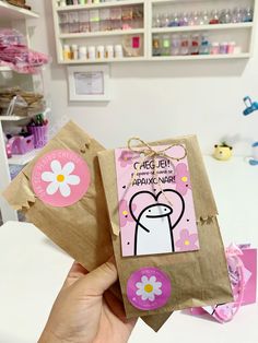 a person holding up a brown paper bag with pink and white flowers on the front