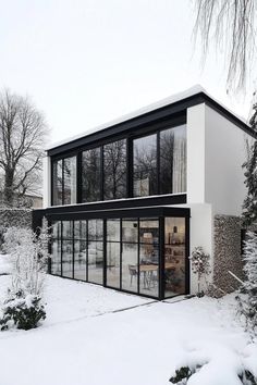 a modern house is covered in snow and has large windows that look out onto the yard