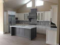 an empty kitchen with white cabinets and gray appliances