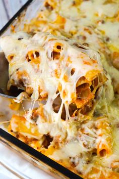 a casserole dish with meat and cheese being lifted from the casserole