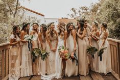 a group of women standing next to each other wearing dresses and holding bouquets in their hands