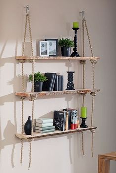 three wooden shelves with books and plants on them hanging from the side of a wall