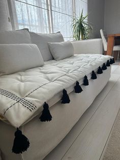 a white couch with black tassels on it