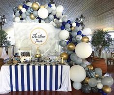 a table is set up with balloons and decorations for a party or celebration in blue, white and gold