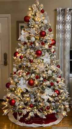 a white christmas tree with red and silver ornaments