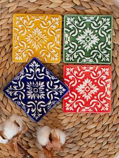 four different colored tiles sitting on top of a wicker basket next to cotton floss