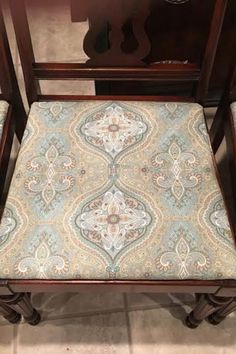 an upholstered chair sitting on top of a tile floor next to a wooden table