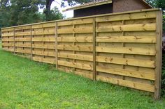 a wooden fence in the grass next to a house